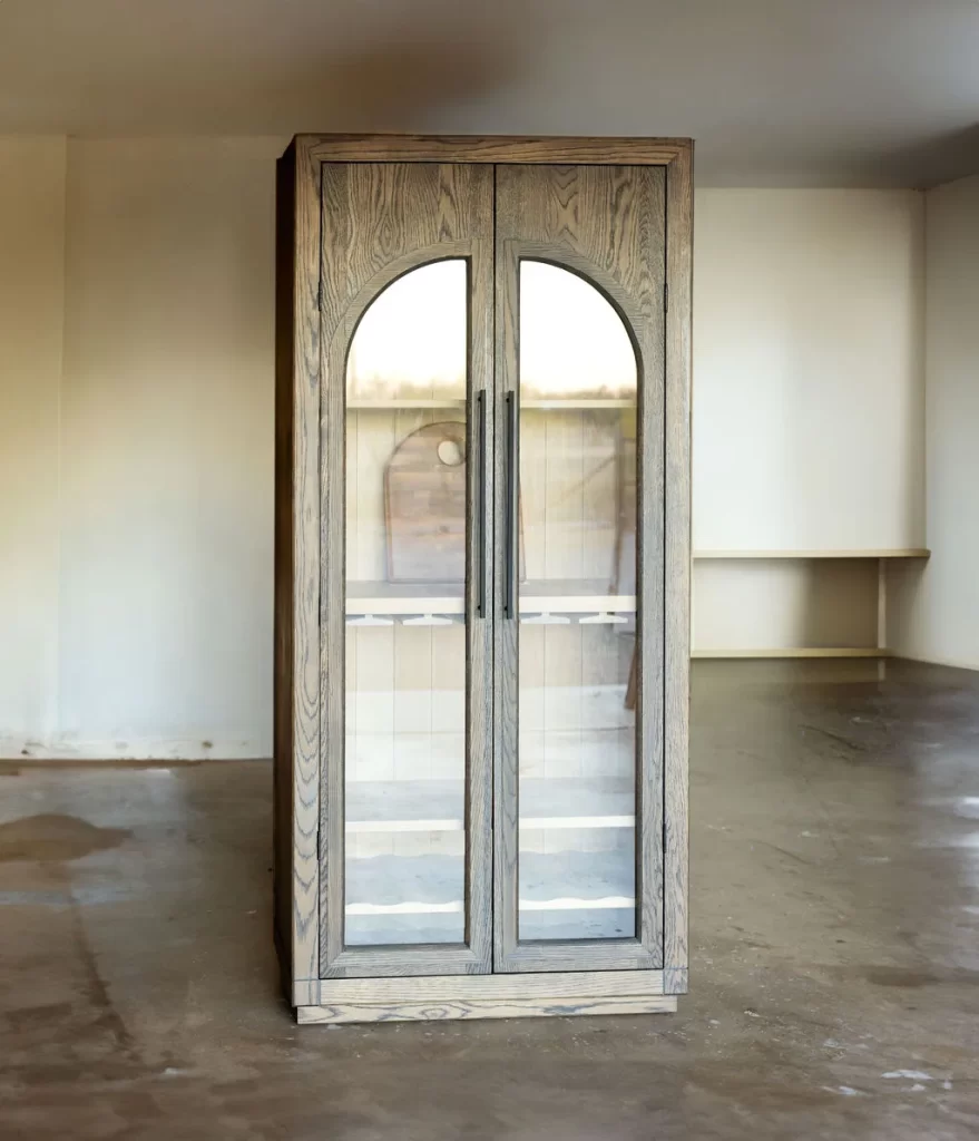 Front view of a custom solid wood bar cabinet in white oak with arched glass doors, oil-rubbed bronze hardware, and plinth base — beth & co. woodworks, Sierra Vista, AZ